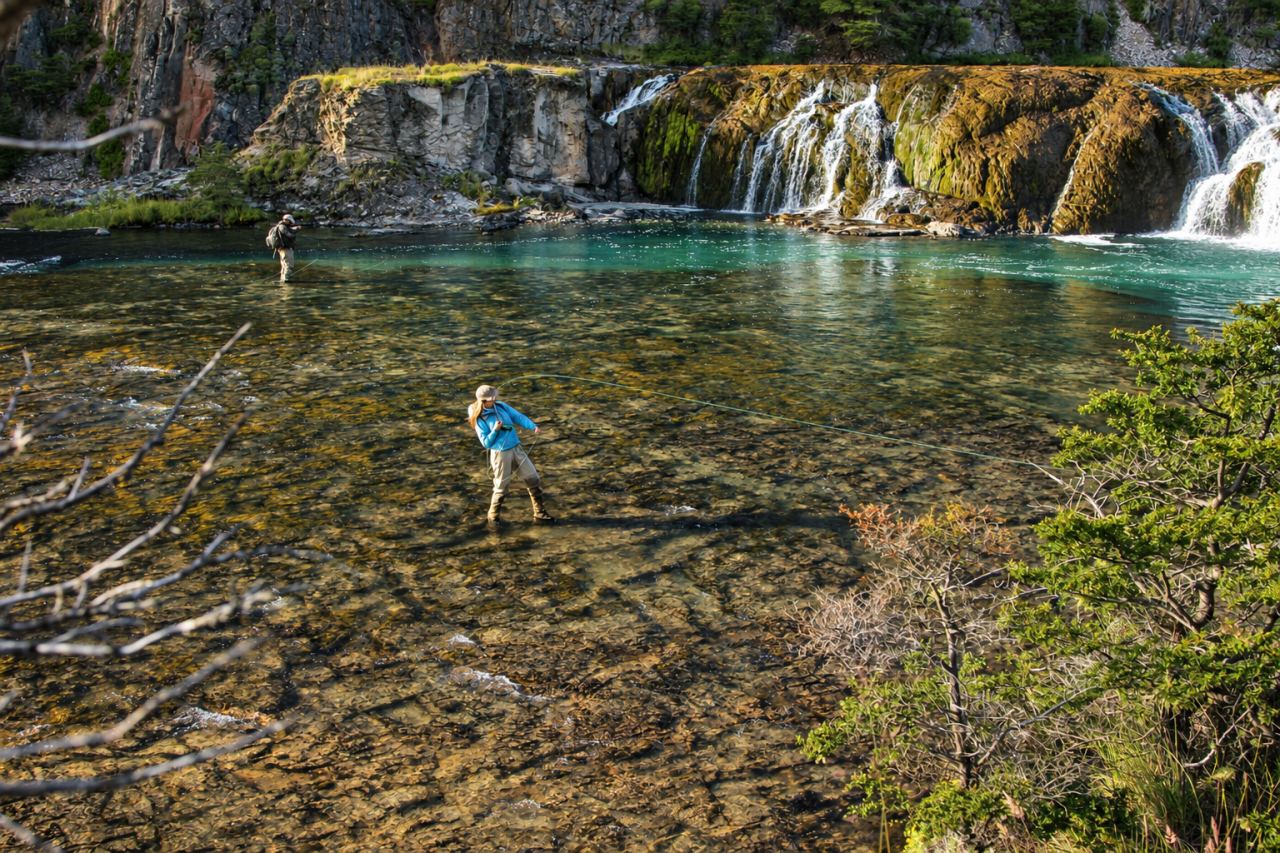 Angler wading a shallow pool fed by cascades