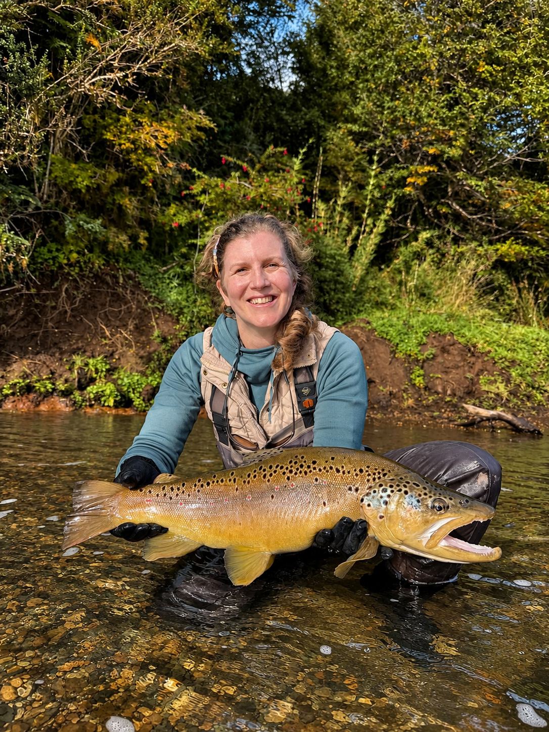 Angler with a brown trout among autumn colours
