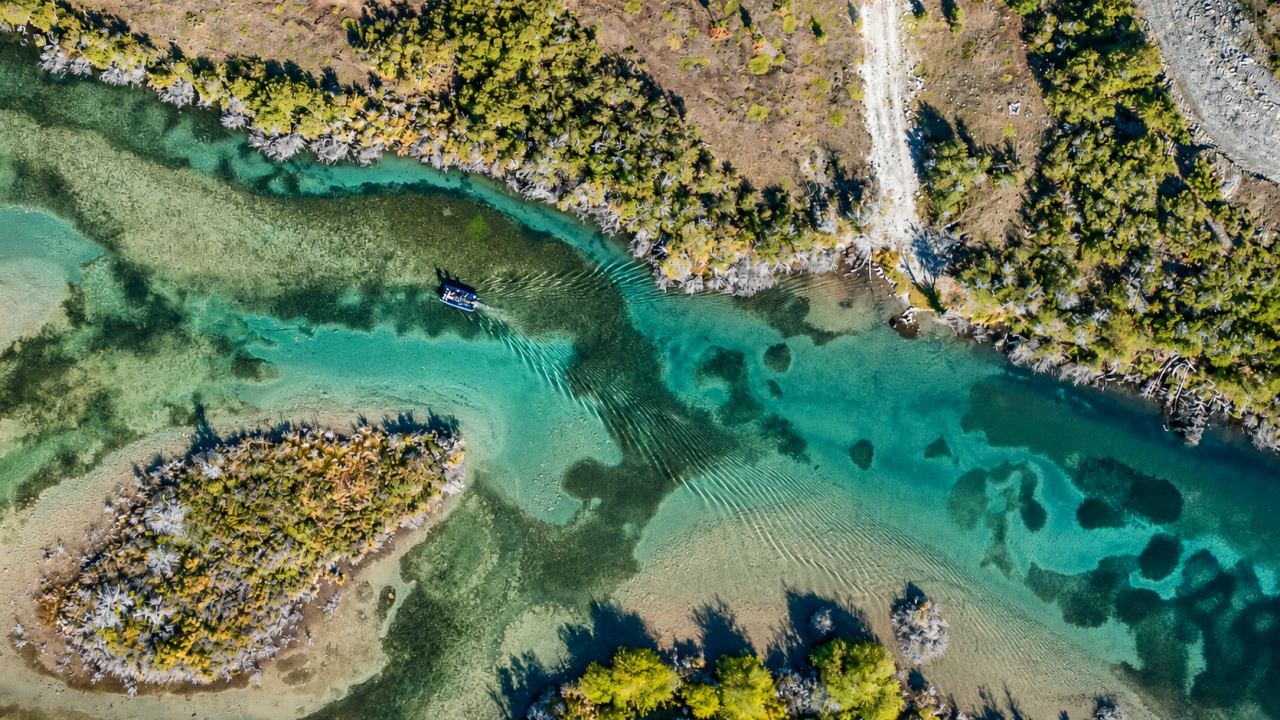 Aerial view of a wooded island in a turquoise river channel